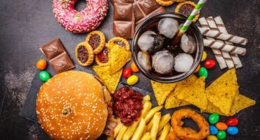 Hamburger, patates kızartması ve içecekten oluşan klasik fast food menüsünün yer aldığı iştah açıcı bir masa.