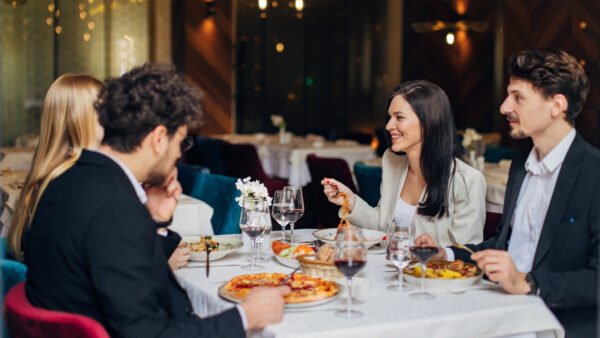 Şık masa düzeni, sıcak ışıklar ve özenli yemek sunumuyla hem lezzeti hem atmosferi hissettiren davetkar bir restoran ortamı.