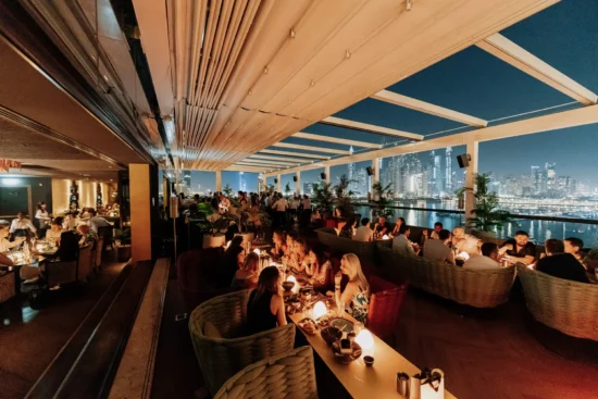 Sıcak ışıklarla aydınlatılmış, şık masa düzenine sahip davetkar bir restoran iç mekanı.